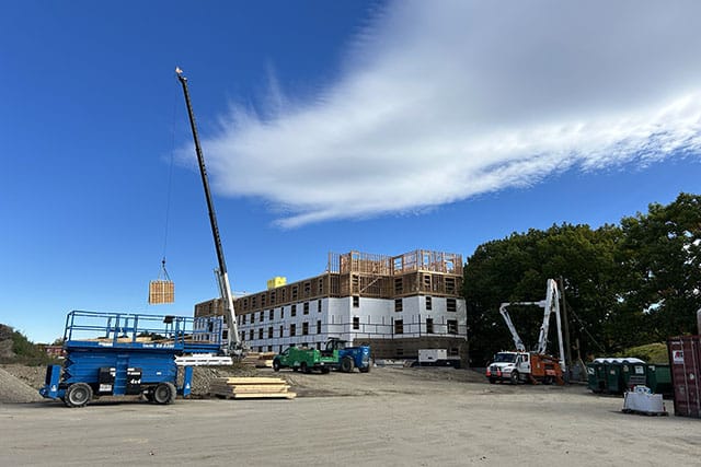Crane lifting wood siding in front of partially complete 45 Dougherty building.